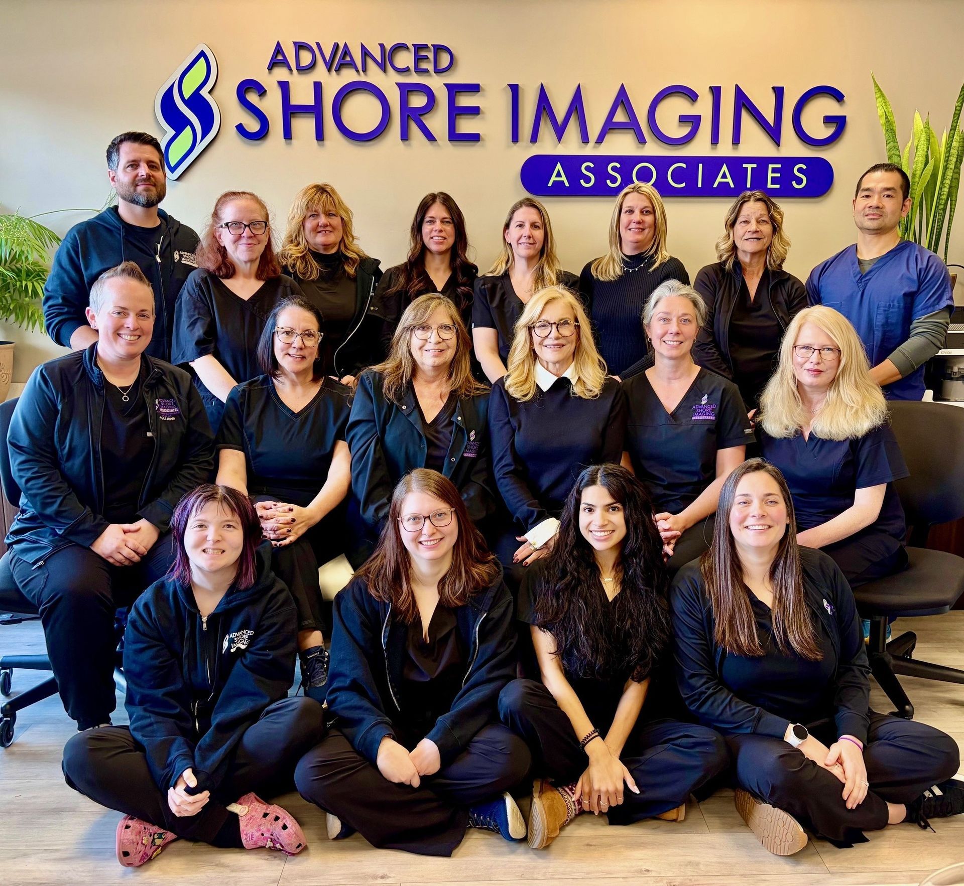 Group staff photo in front of Shore Imaging Associates sign, with people posing in navy uniforms