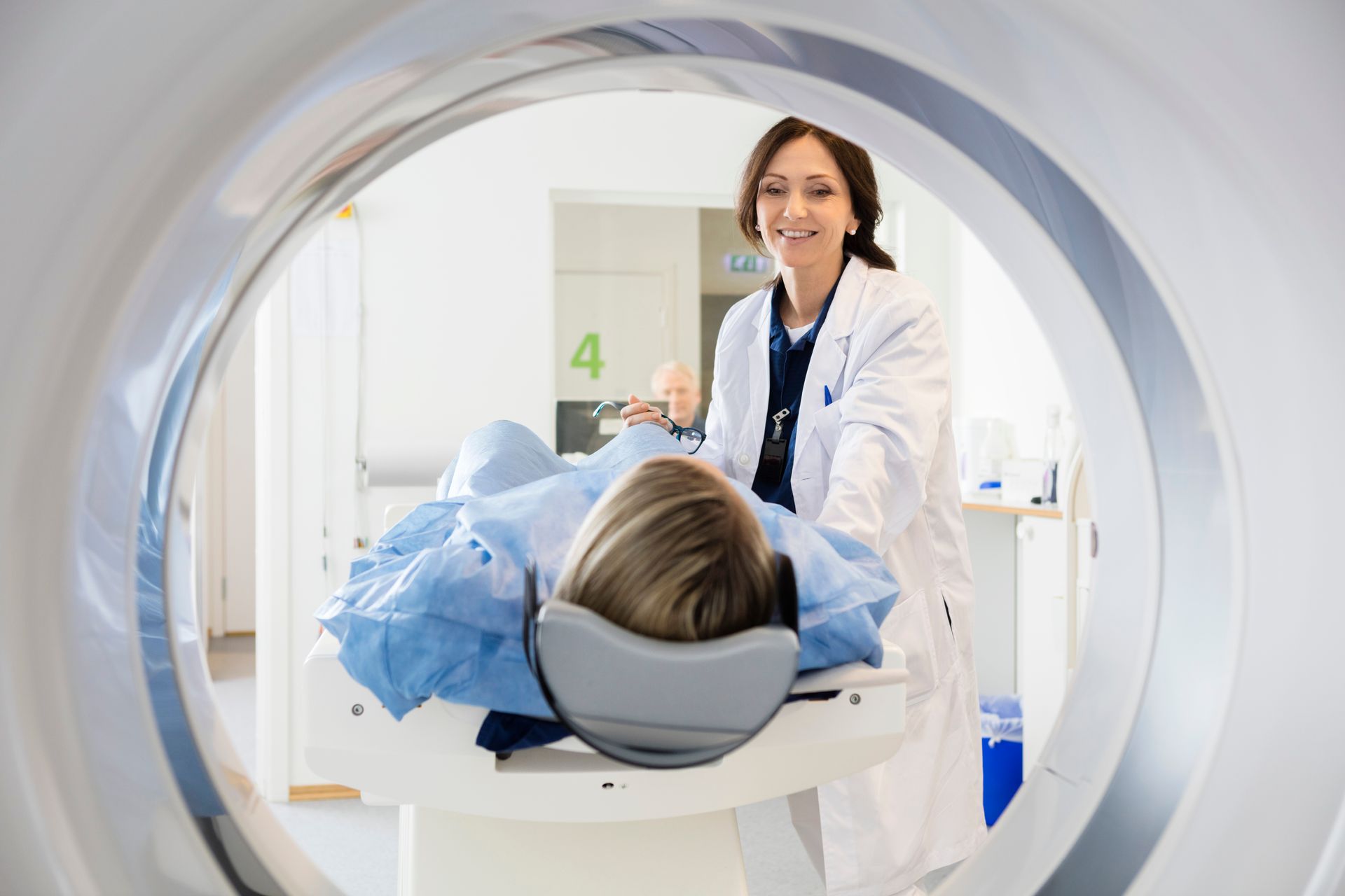 Doctor smiling at patient in MRI scanner, viewed through the circular opening