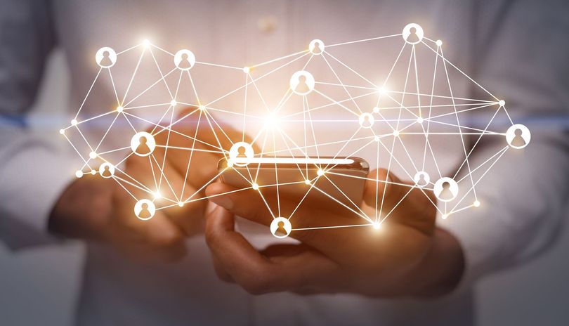 Hands holding a smartphone with a glowing digital network overlay