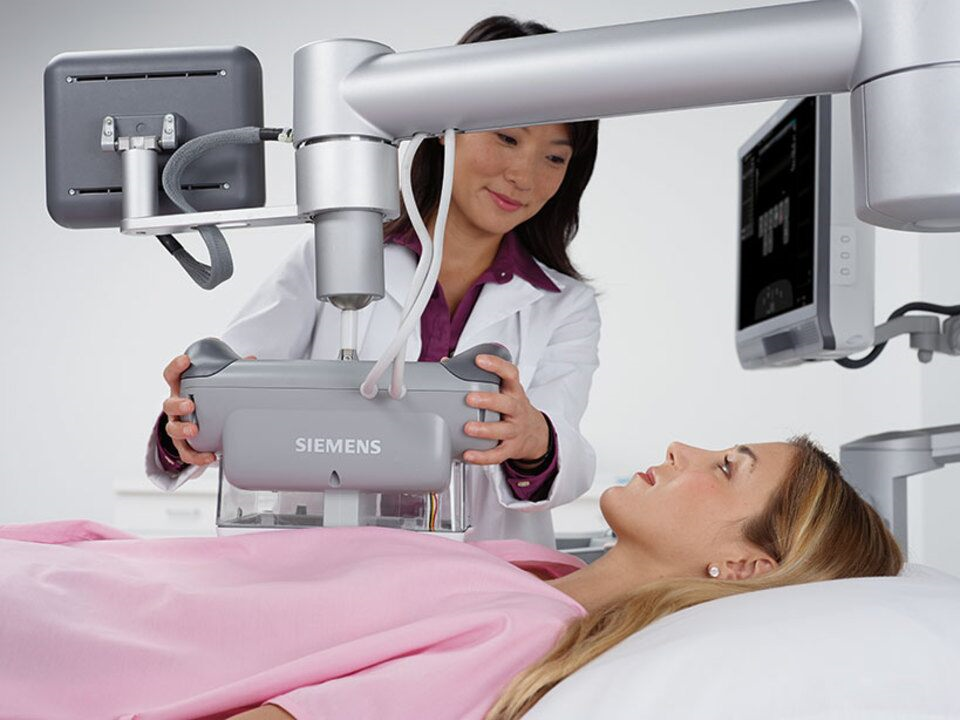 Medical professional using ultrasound machine on patient lying on exam table