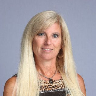 Smiling blonde woman in a patterned top against a plain gray background