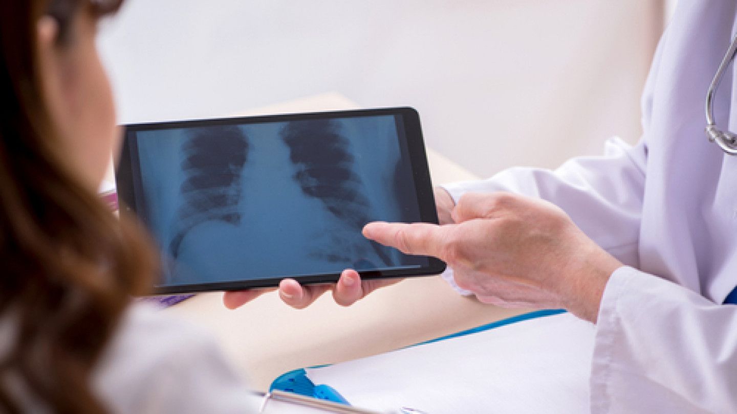 Doctor showing a chest X-ray on a tablet to a patient in a clinical setting