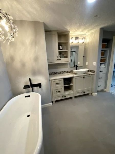 Modern bathroom with freestanding tub, vanity, mirror, and built-in shelves in a light gray interior