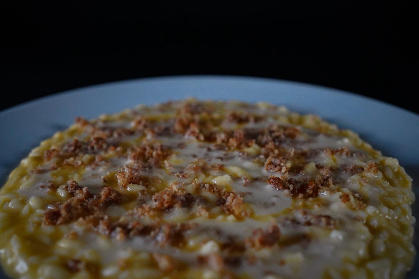 Primo piano di una pietanza gratinata con una crosticina dorata, servita su un piatto bianco