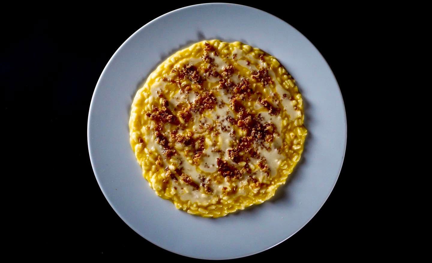 Una pizza rotonda al salame piccante su un piatto grigio chiaro, su uno sfondo nero
