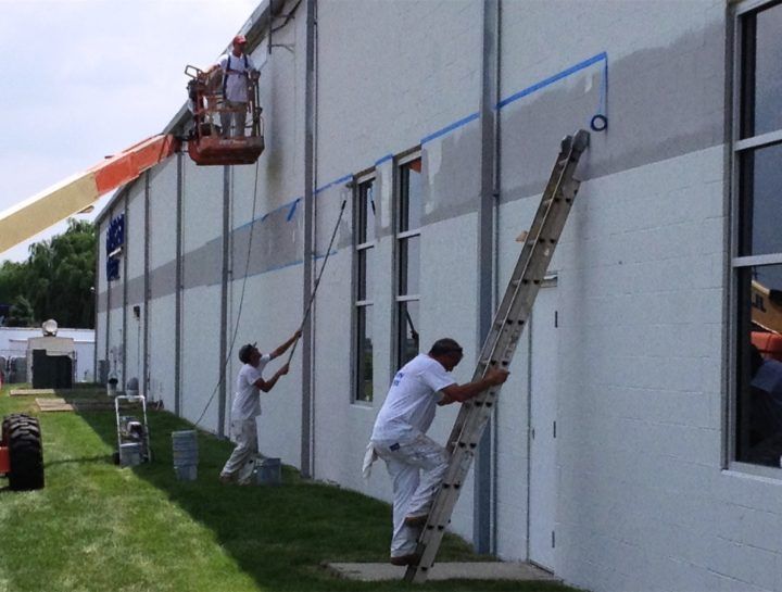 Painter applying exterior paint to a retail storefront