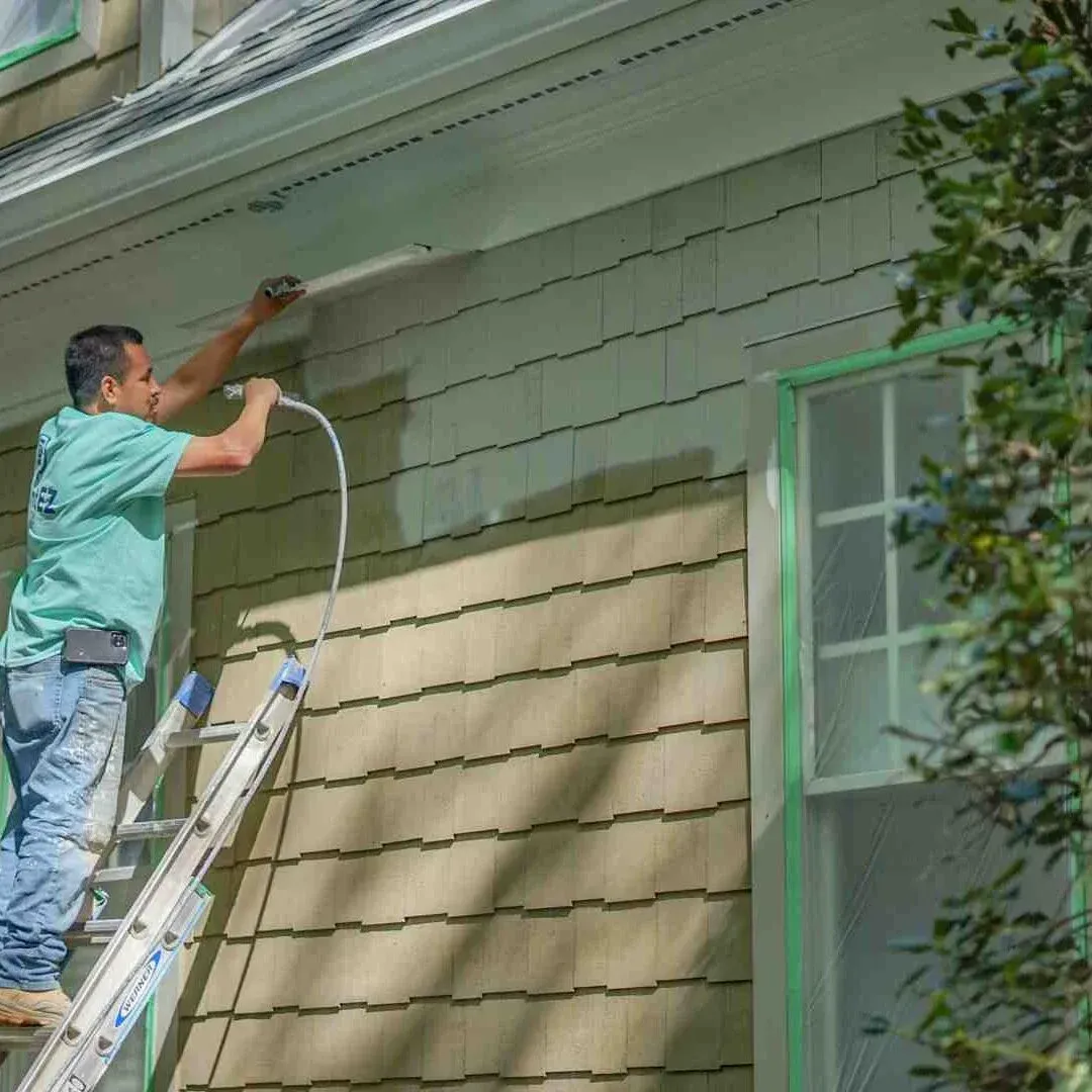 Painter applying exterior paint to house siding