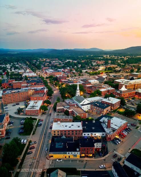 Aerial view of a colorful downtown at sunset with roads, buildings, and distant hills