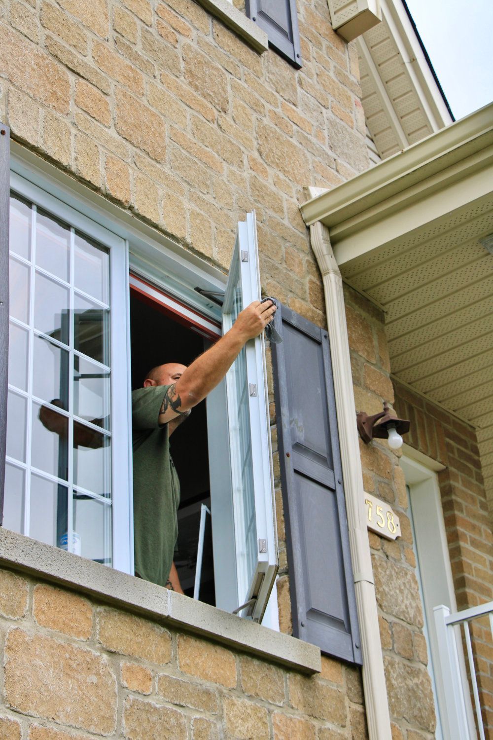 Person opening a window on a stone building exterior