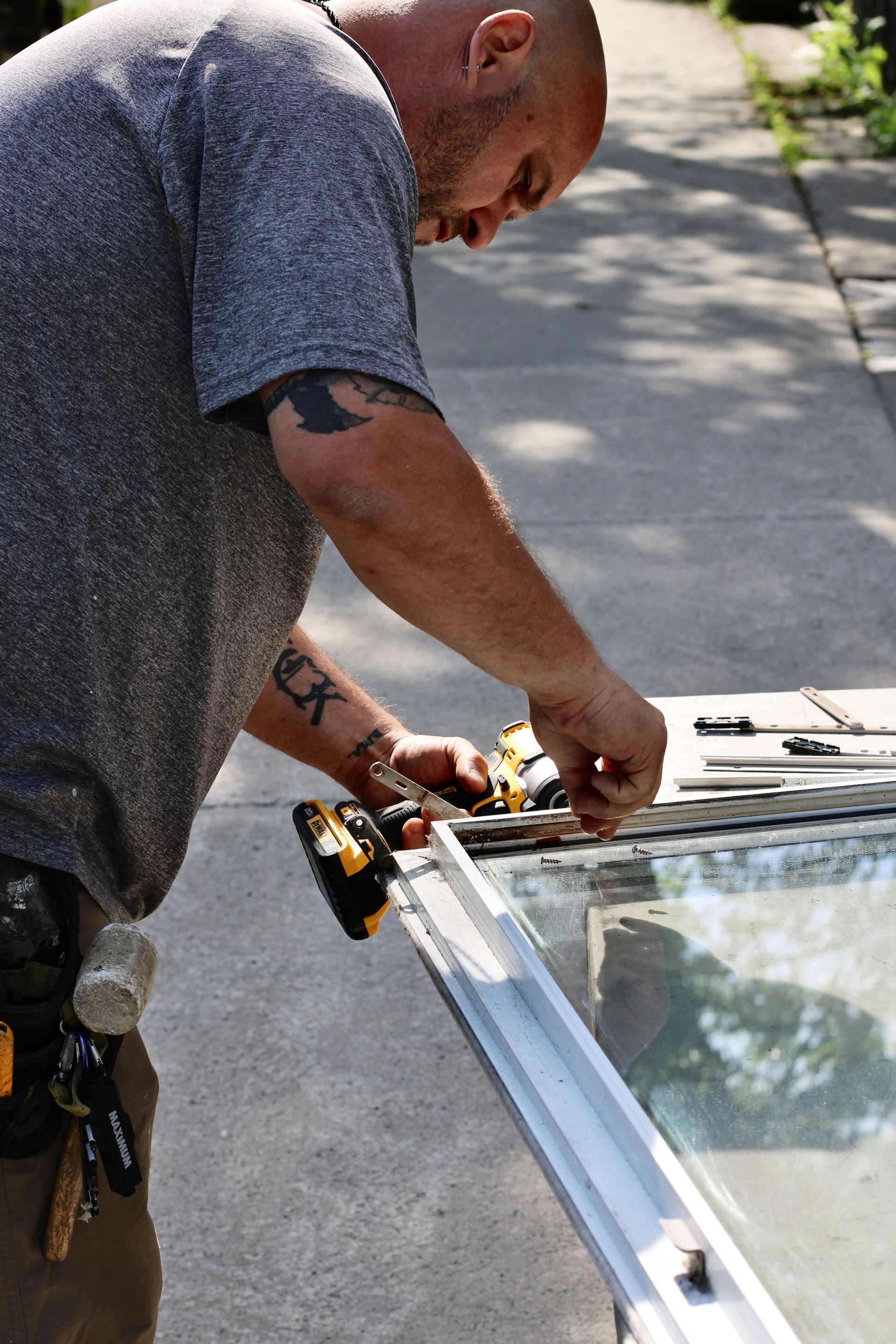 Worker repairing a window frame outdoors with tools on a sunny day