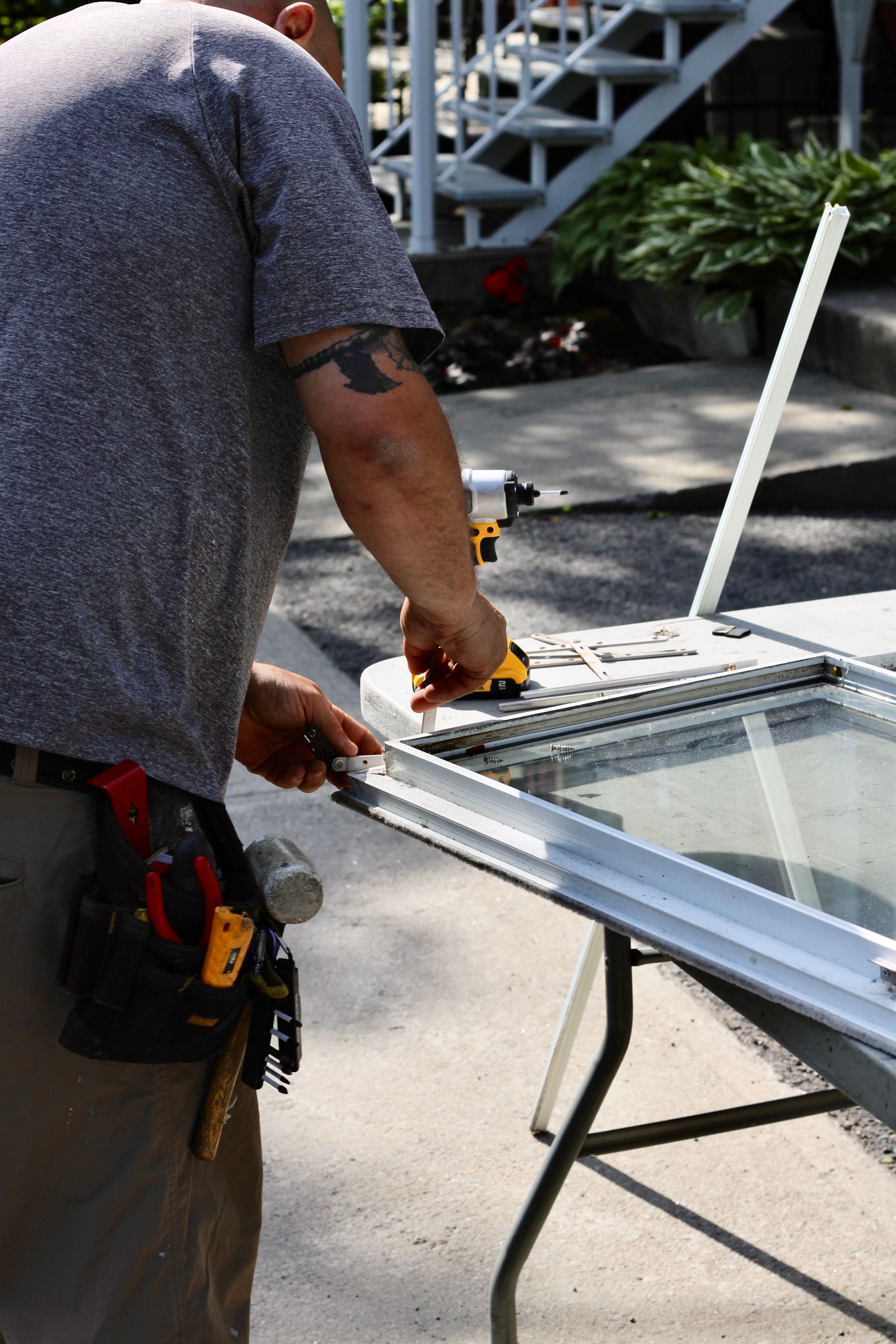 Worker measuring a window frame on a table outdoors with tools nearby