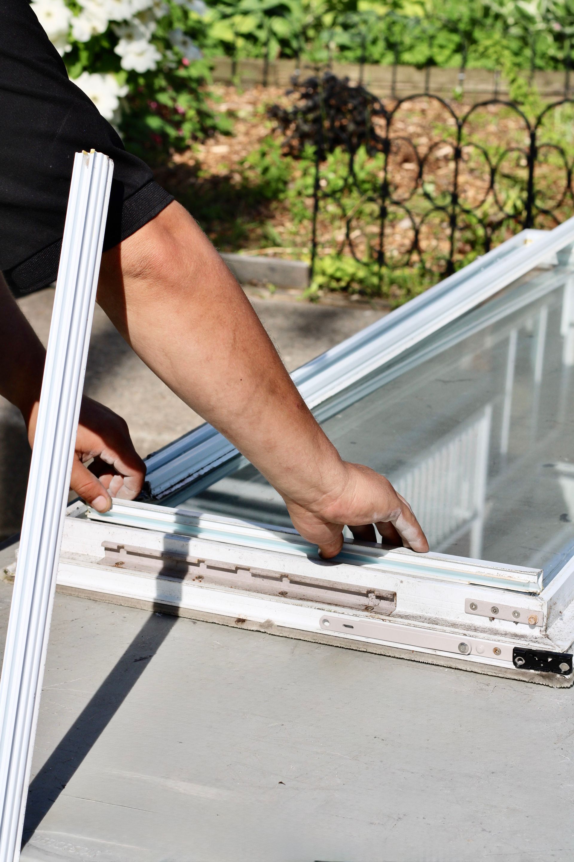 Person installing a white skylight frame on a roof outdoors