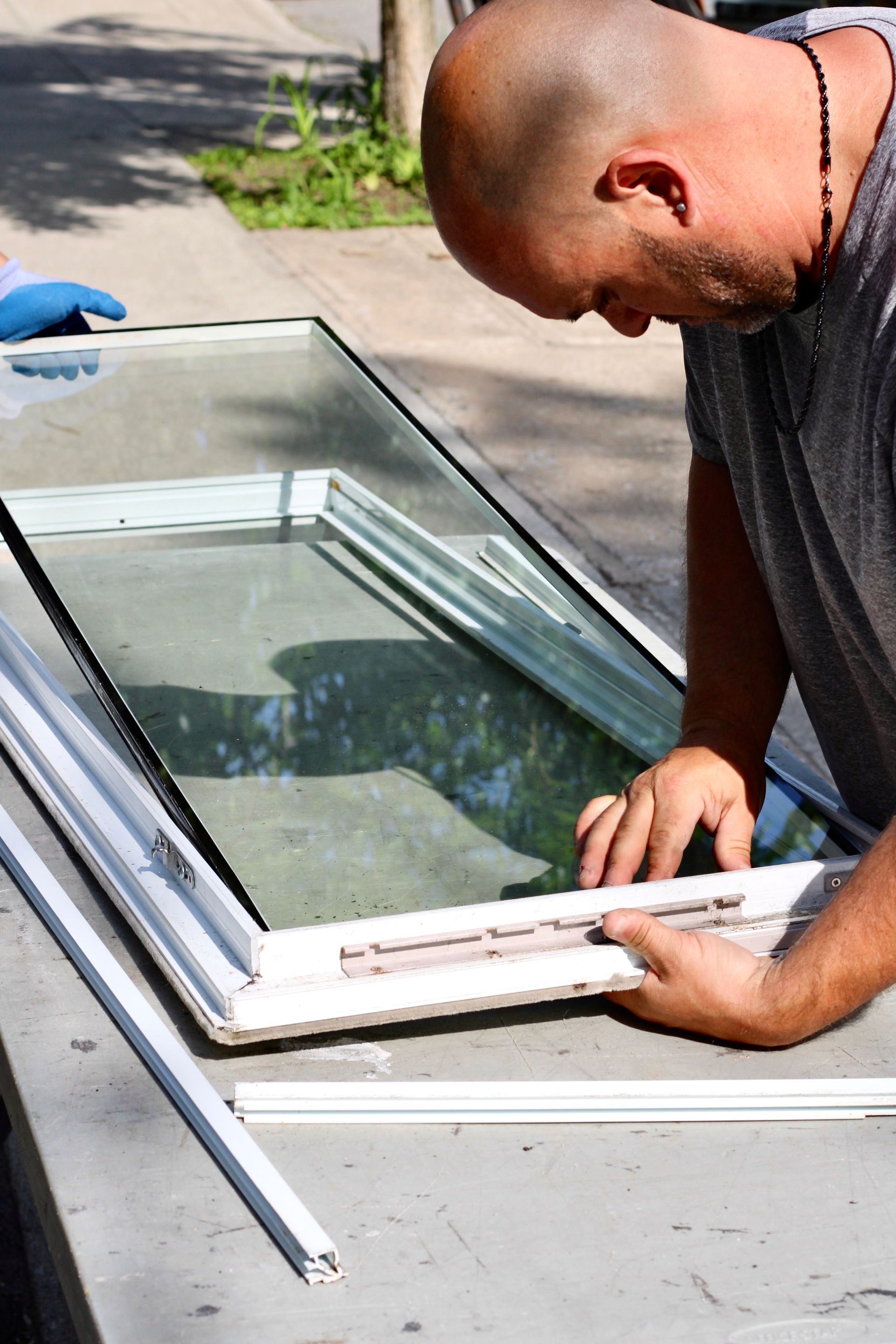 Person installing a white window frame into a roof window opening outdoors
