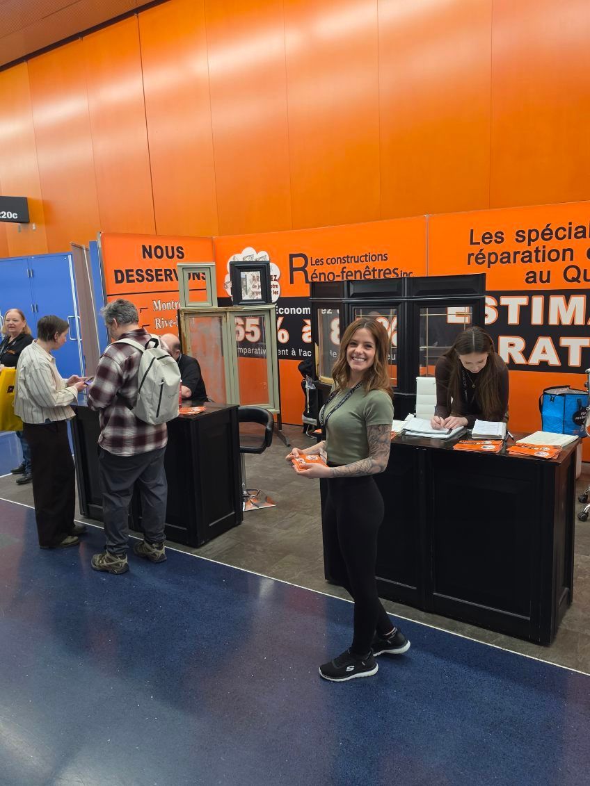 Orange expo booth with a woman standing in front and people browsing nearby