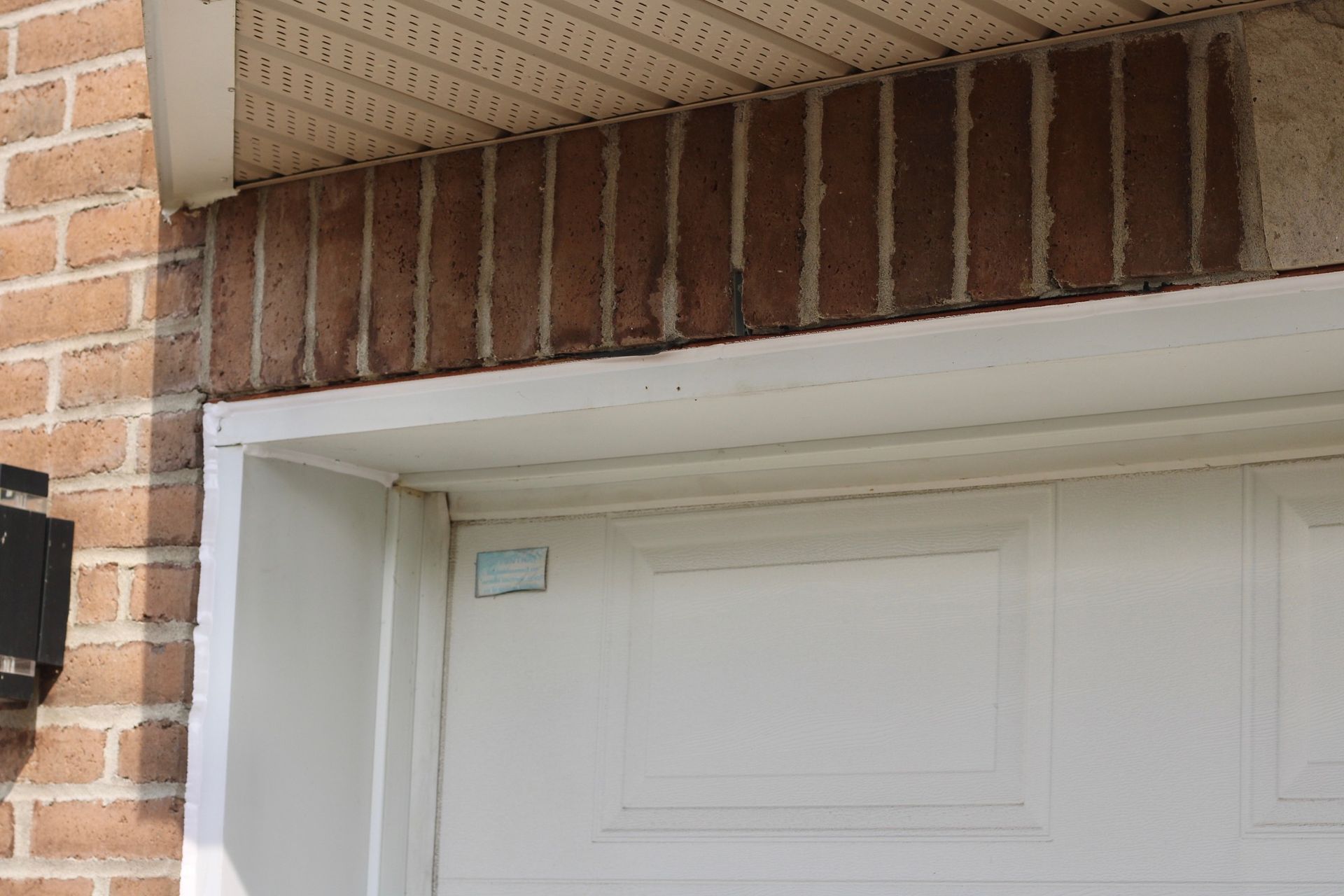 Brick house entry above a white garage door with a brick lintel and white trim