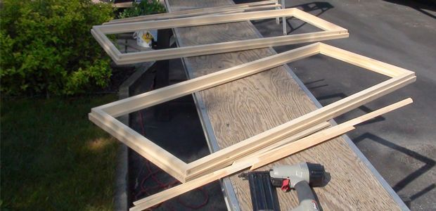 Several wooden window frames laid out on a dock or bridge over water