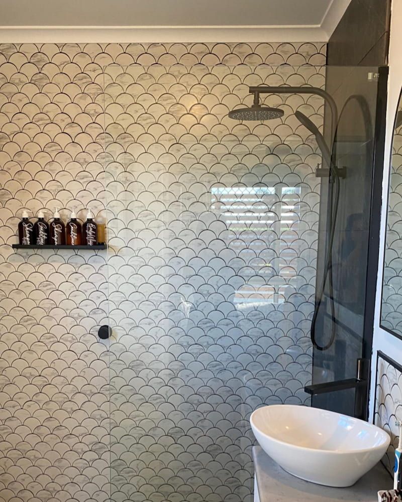 A Bathroom With A Sink And A Shower With A Fish Scale Pattern On The Wall — Pioneer Cabinets in Rural View, QLD