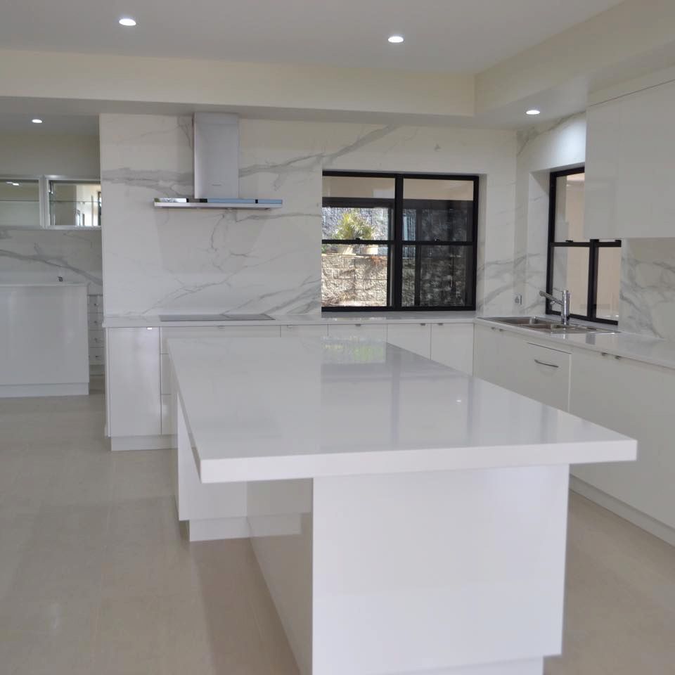 A Kitchen With White Cabinets And A Large White Island — Pioneer Cabinets in Paget, QLD