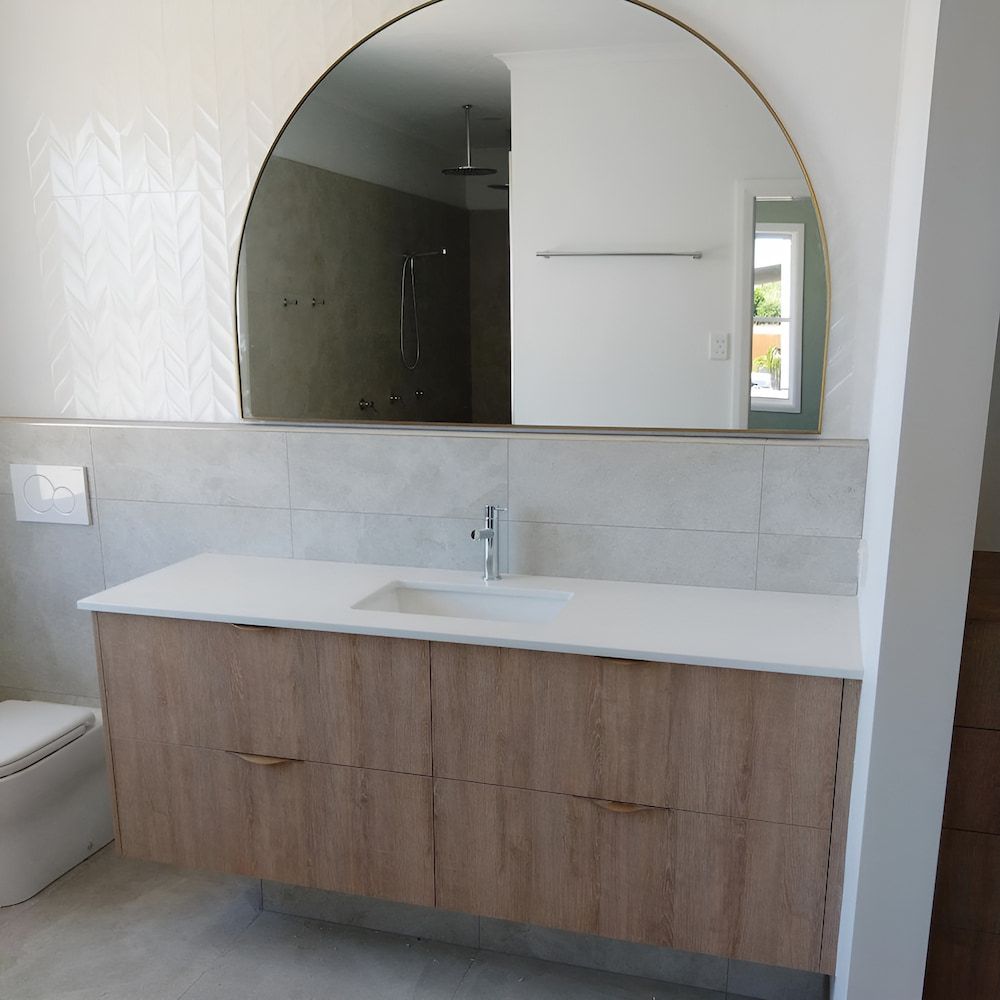 A Bathroom With A Sink And A Large Mirror — Pioneer Cabinets in Paget, QLD