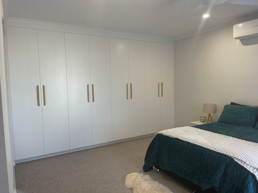 A Bedroom With A Bed, Closets And A Dog — Pioneer Cabinets in Airlie Beach, QLD