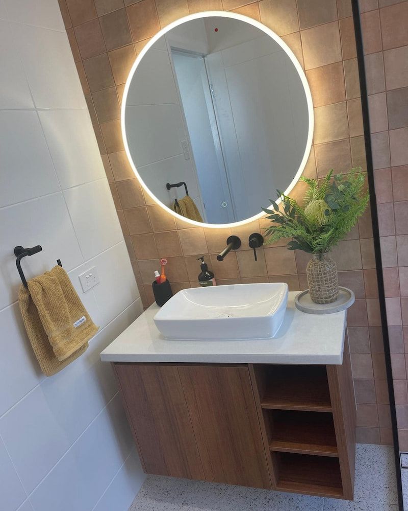 A Bathroom With A Sink And A Round Mirror — Pioneer Cabinets in Paget, QLD