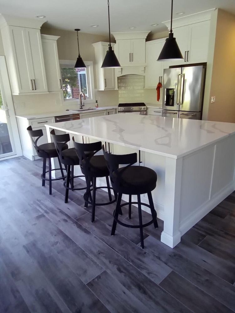 A Kitchen With A Large Island And Stools — Pioneer Cabinets in Sarina, QLD