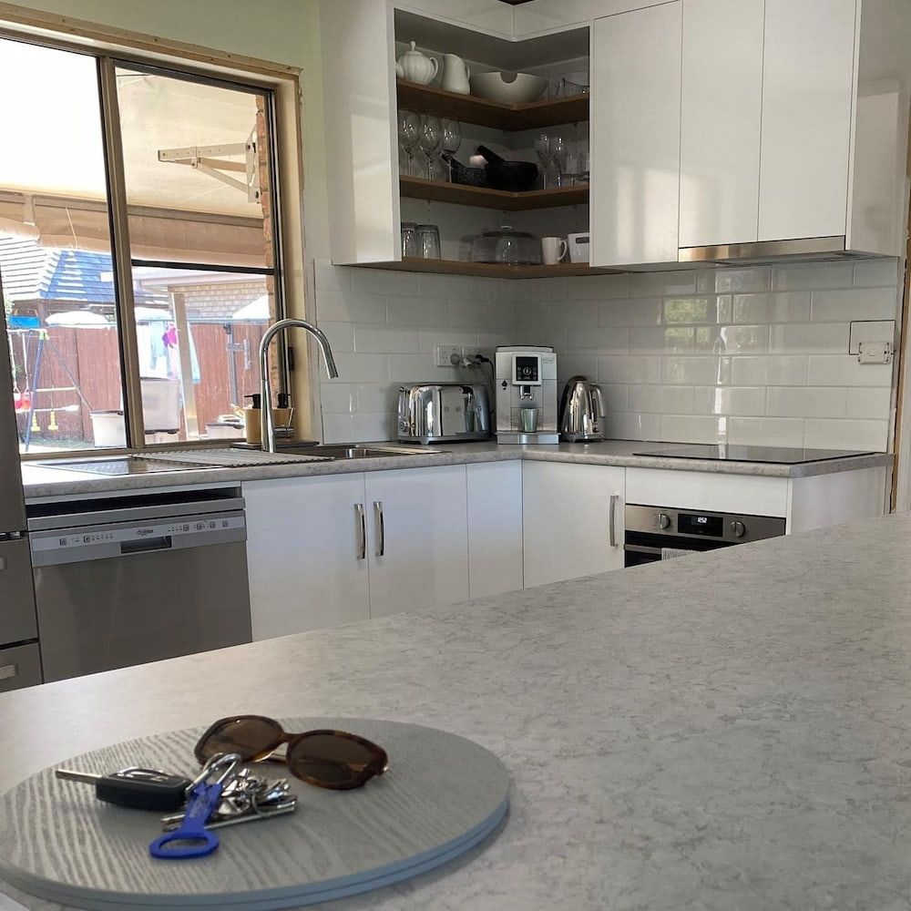 A Kitchen With White Cabinets And Stainless Steel Appliances — Pioneer Cabinets in Paget, QLD