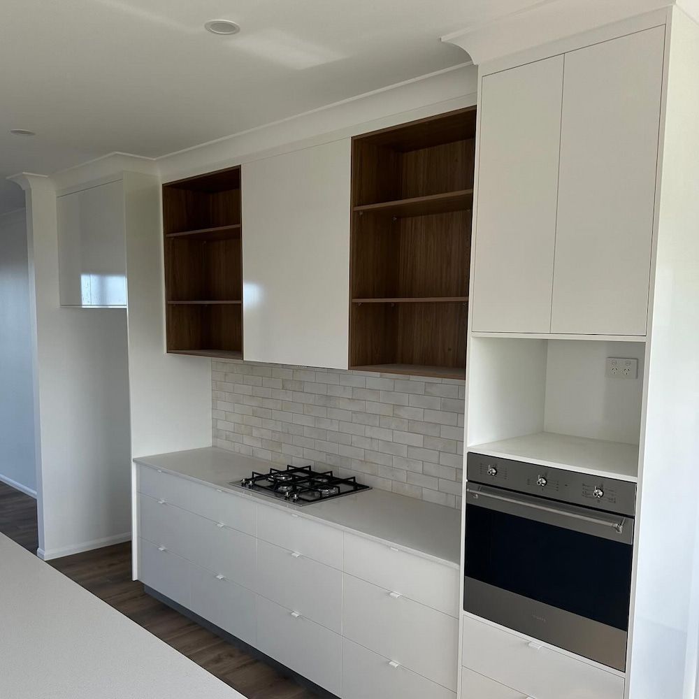 A Kitchen With White Cabinets, A Stove Top Oven — Pioneer Cabinets in Sarina, QLD