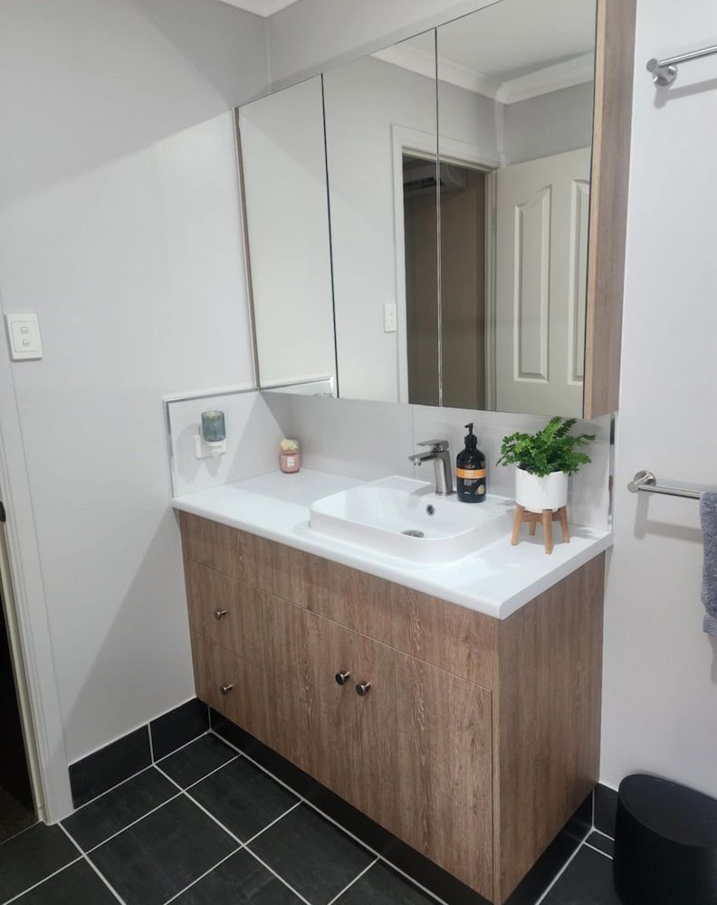 A Bathroom With A Sink, Mirror And Cabinets — Pioneer Cabinets in Paget, QLD