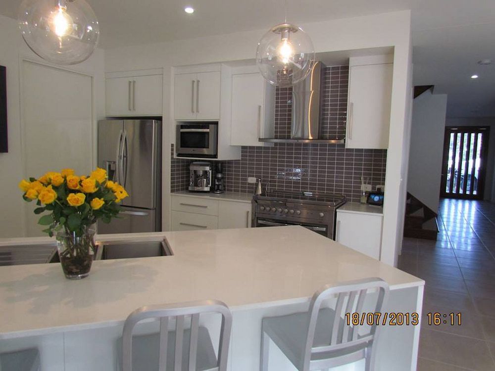 A Kitchen With A Vase Of Yellow Roses On The Counter — Pioneer Cabinets in Airlie Beach, QLD