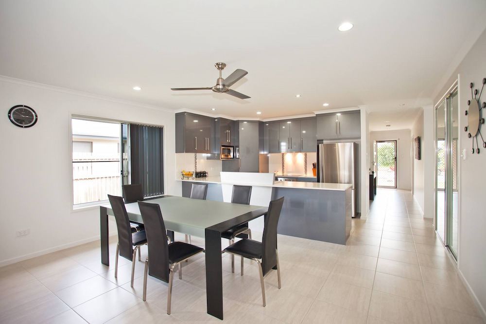 A Kitchen With A Table And Chairs And A Ceiling Fan — Pioneer Cabinets in Rural View, QLD