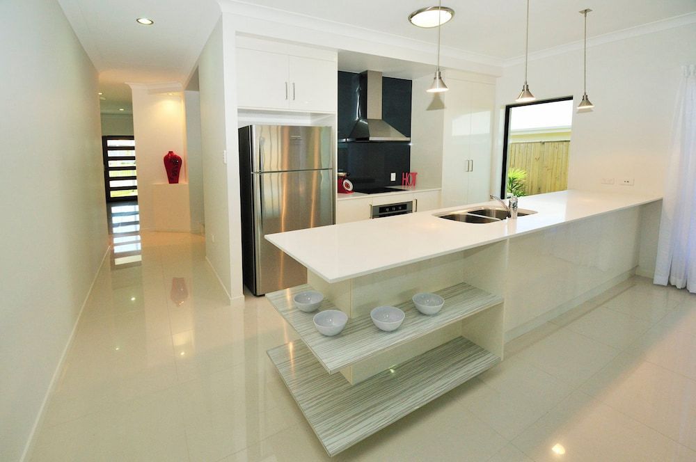 A Kitchen With White Countertops And A Stainless Steel Refrigerator — Pioneer Cabinets in Paget, QLD
