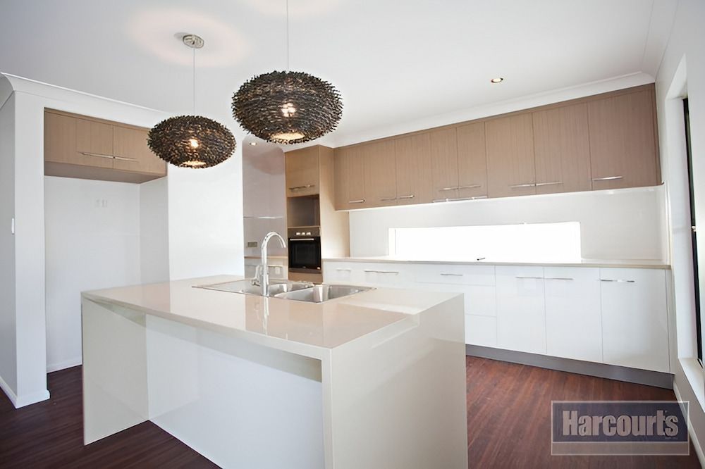 An Empty Kitchen With White Cabinets And A Large Island — Pioneer Cabinets in Rural View, QLD