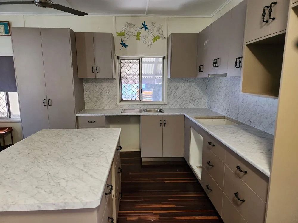 A Kitchen With A Large Island In The Middle Of It — Pioneer Cabinets in Paget, QLD