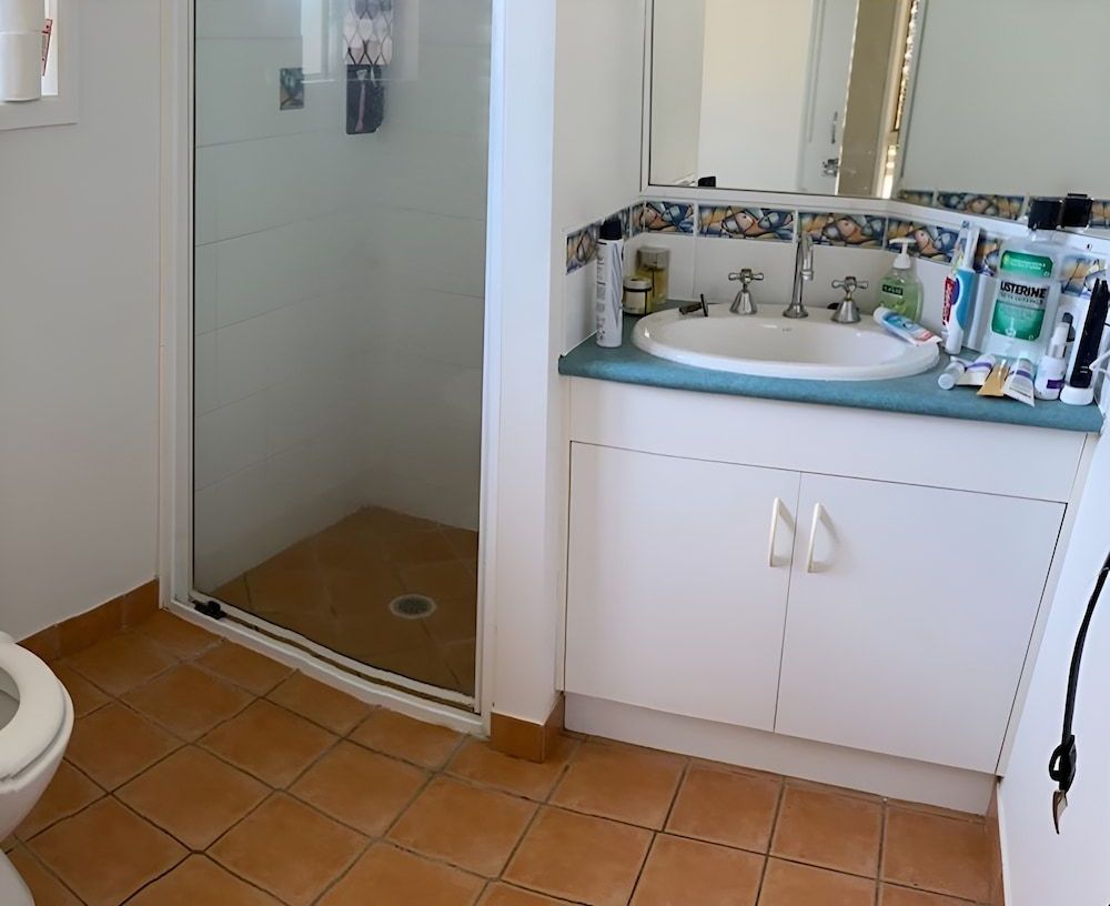 A Bathroom With A Toilet A Sink And A Shower — Pioneer Cabinets in Moranbah, QLD