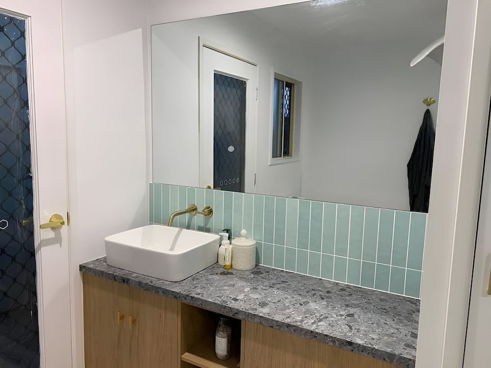 A Bathroom With A Sink And A Large Mirror — Pioneer Cabinets in Rural View, QLD