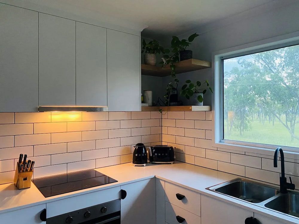 A Kitchen With White Cabinets And Window — Pioneer Cabinets in Paget, QLD