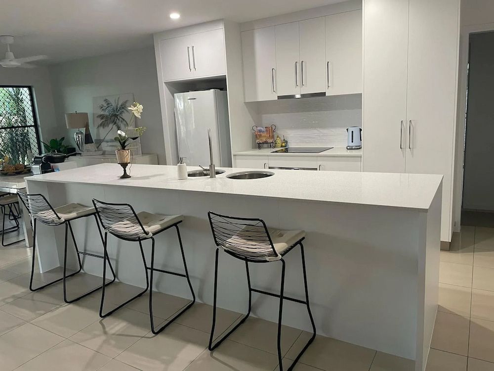 A Kitchen With White Cabinets And Stools — Pioneer Cabinets in Paget, QLD