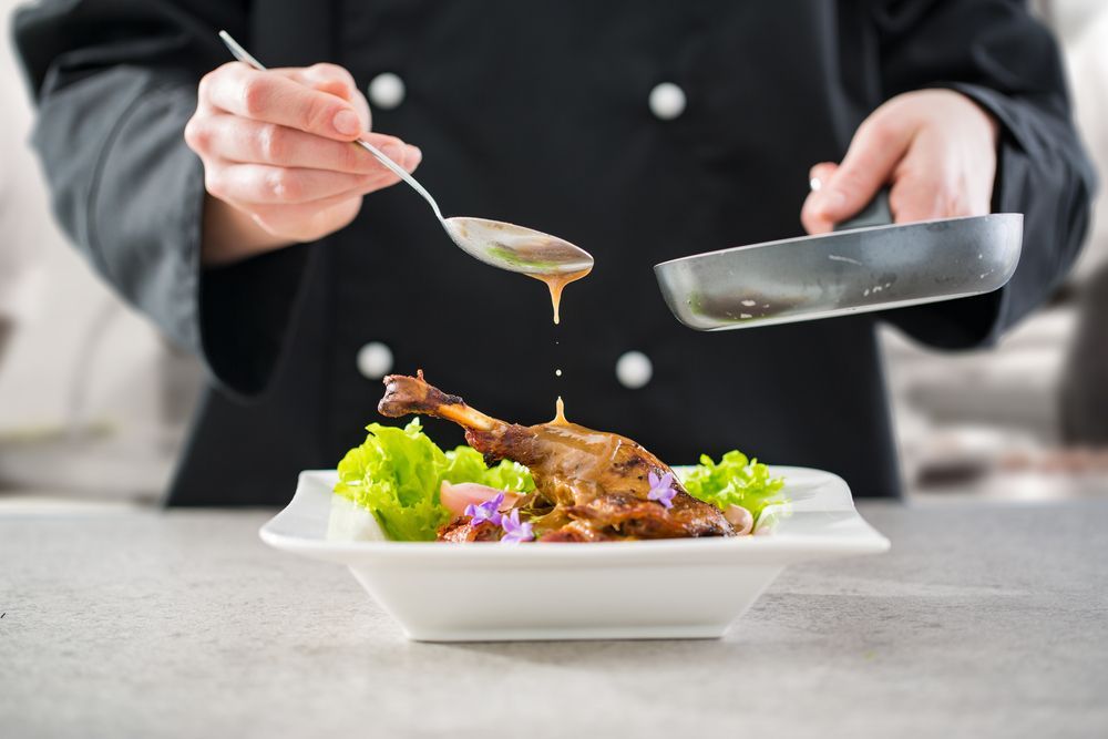 Chef Drizzling Sauce from A Spoon onto A Plated Duck Leg — Mount Louisa Snack Bar in Mount Louisa, QLD