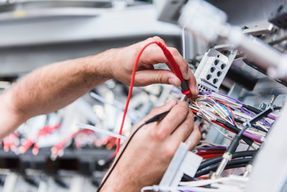 A man is using a multimeter to test a bunch of wires.