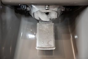 A close up of an ice maker in a refrigerator.
