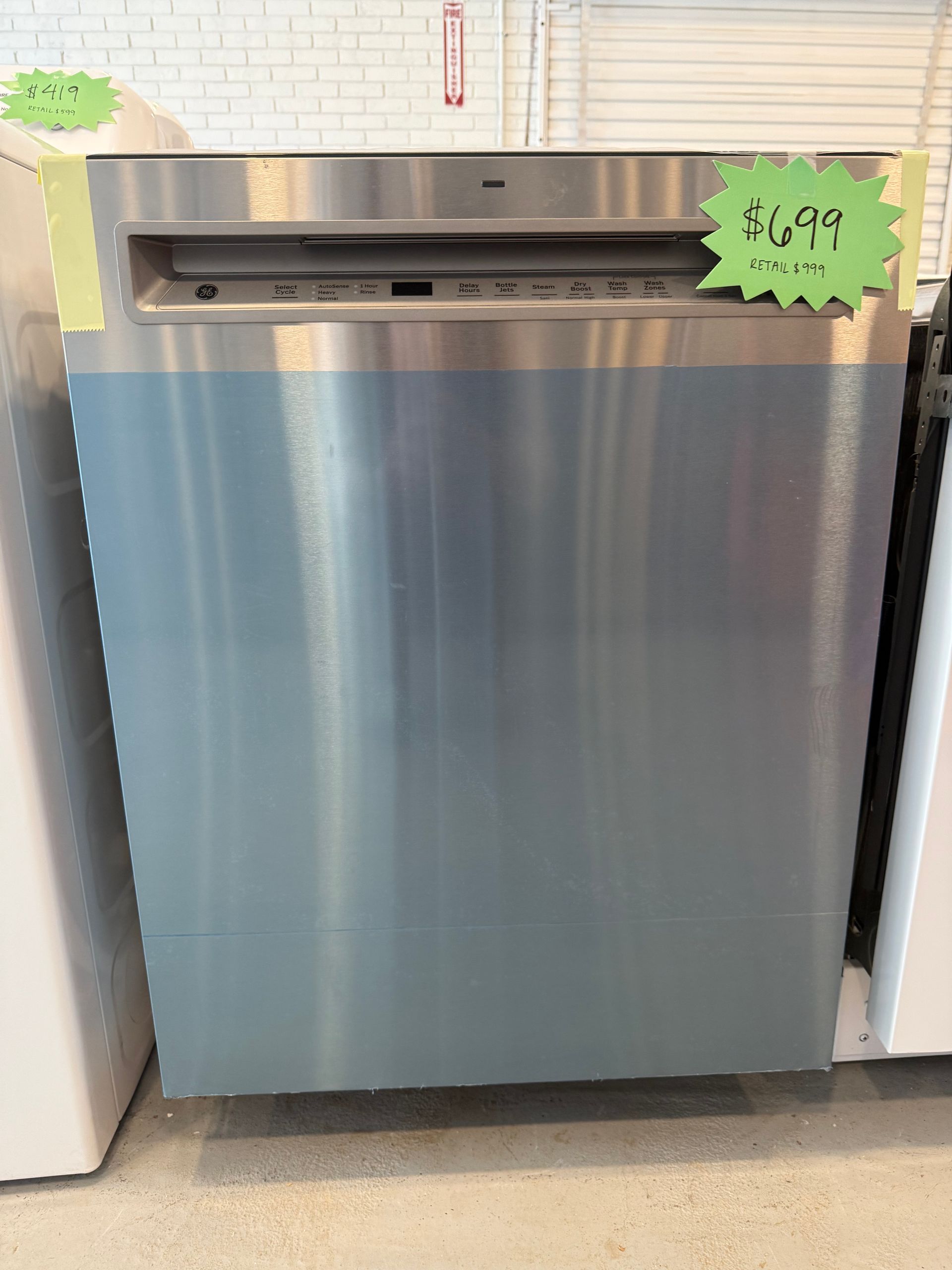 A stainless steel dishwasher is sitting on a counter in a store.