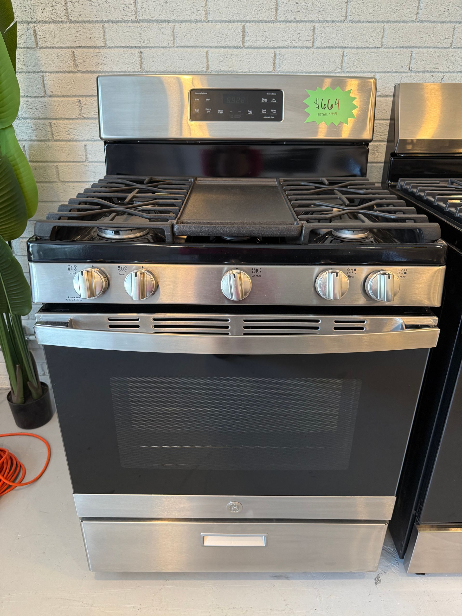 A stainless steel stove with a green tag on it is sitting on a counter.