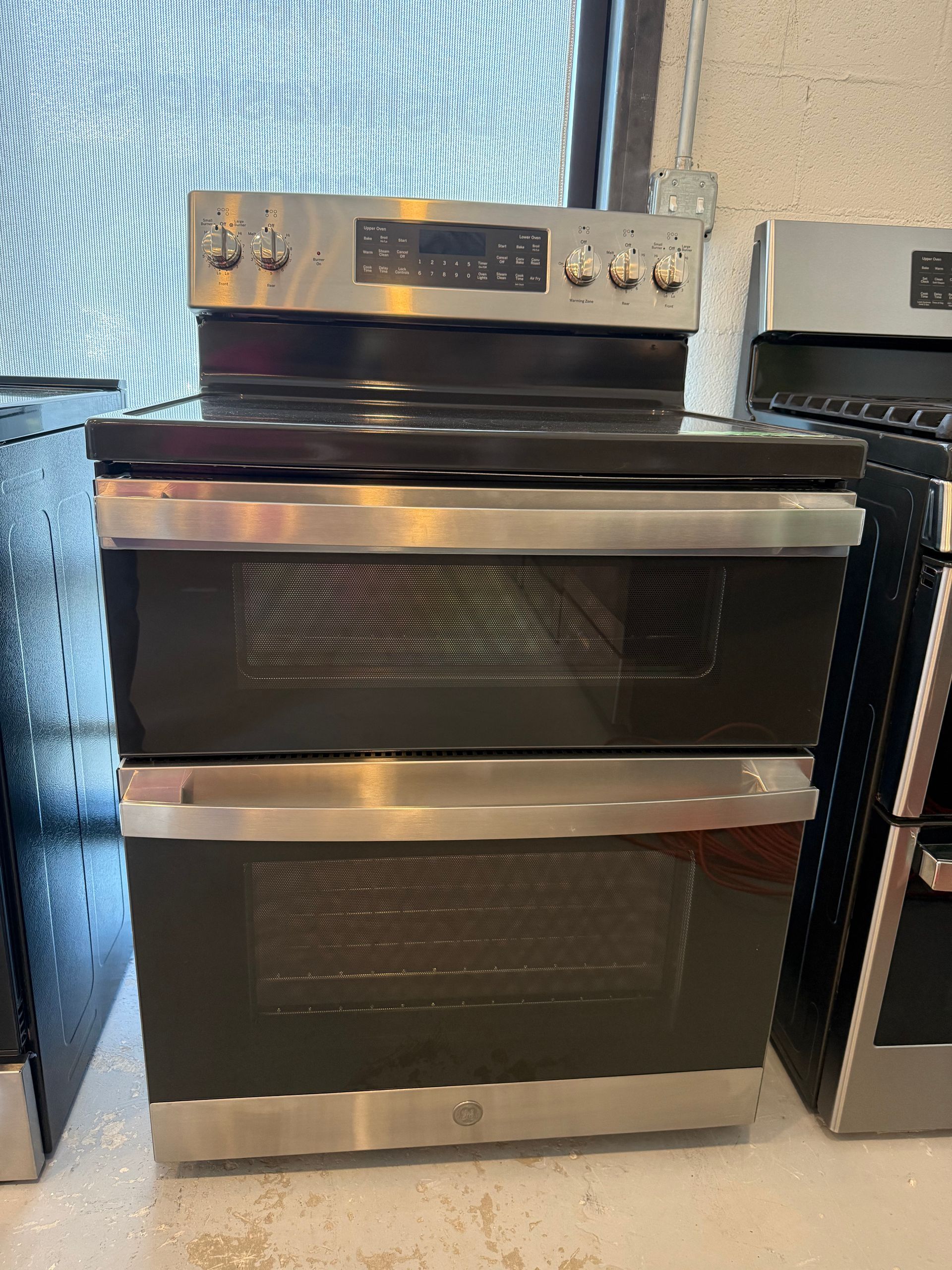 A stainless steel stove top oven is sitting on a counter next to a window.