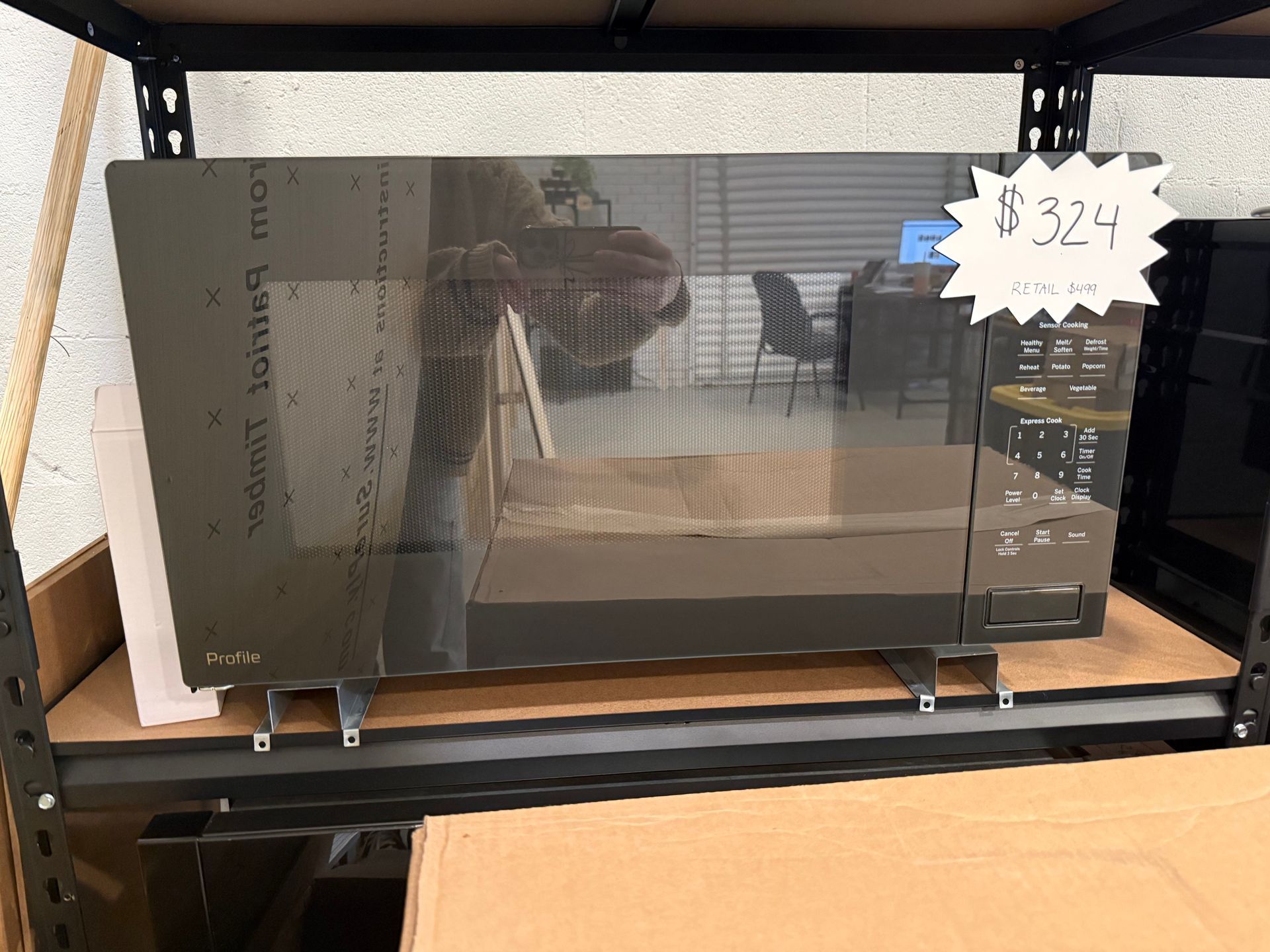 A microwave oven is sitting on a shelf with a price tag of $ 324.