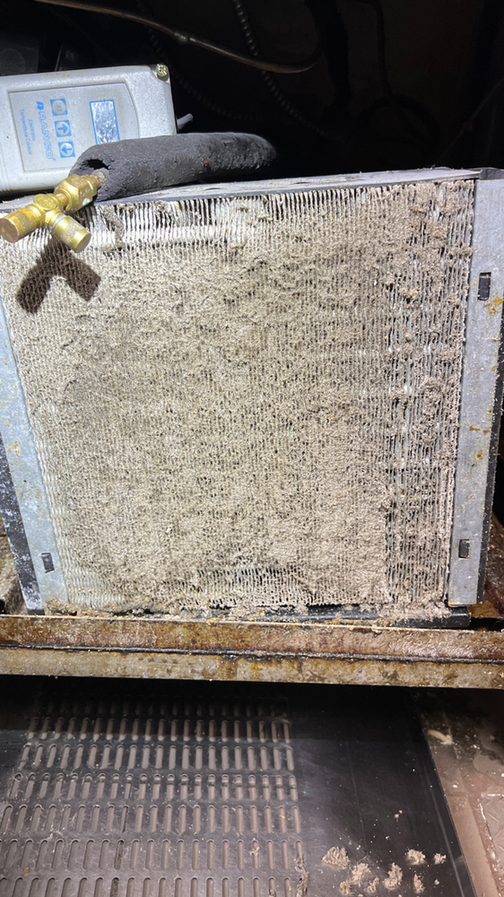 A dirty air conditioner coil is sitting on top of a wooden table.