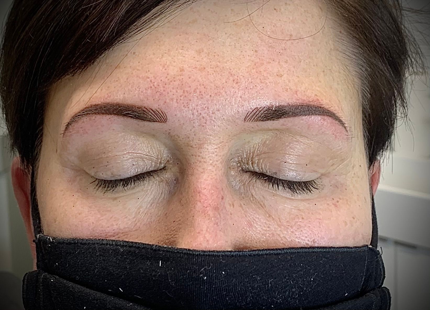 eine Frau trägt eine schwarze Gesichtsmaske mit geschlossenen Augen .