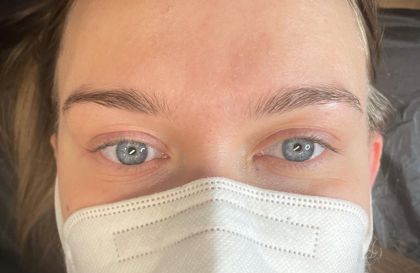 Eine Frau mit blauen Augen trägt eine Gesichtsmaske .