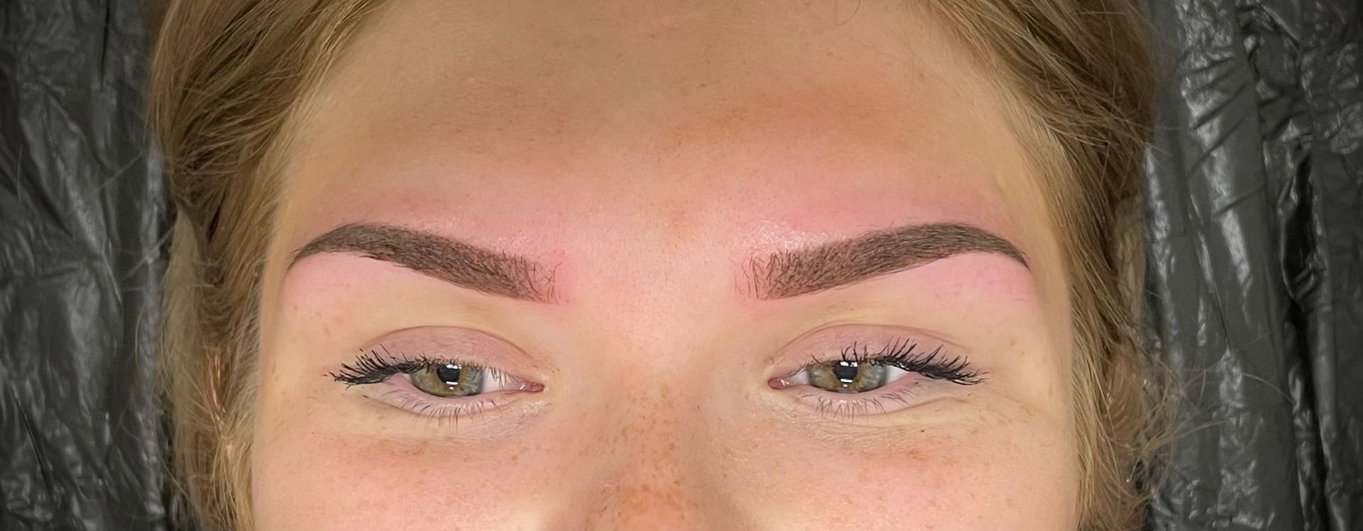 Nahaufnahme einer Frau mit roten Augenbrauen und grünen Augen .