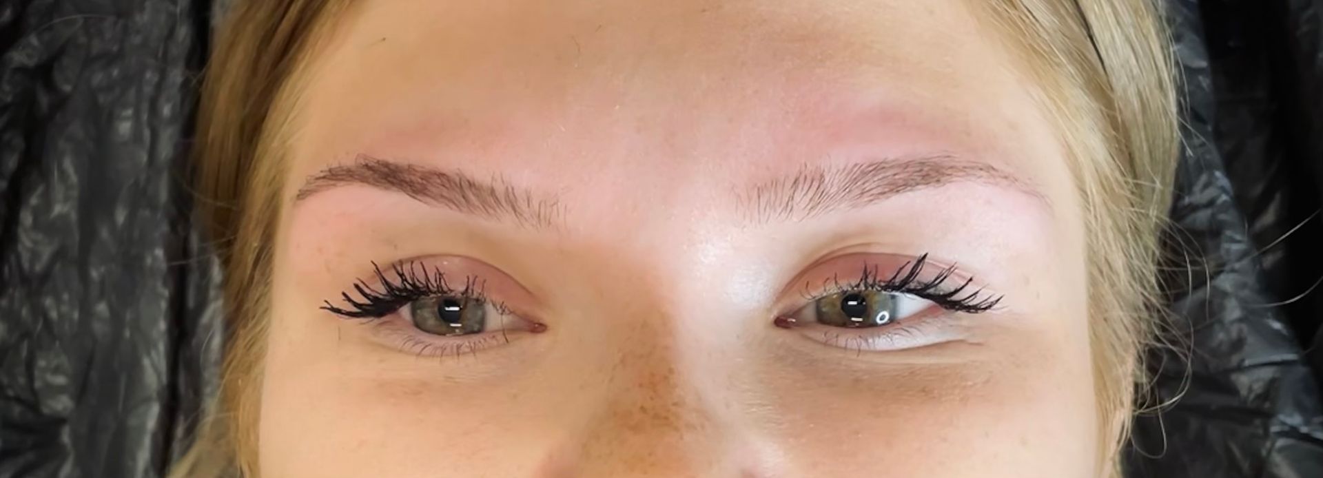 Nahaufnahme einer Frau mit langen Wimpern und braunen Augenbrauen .